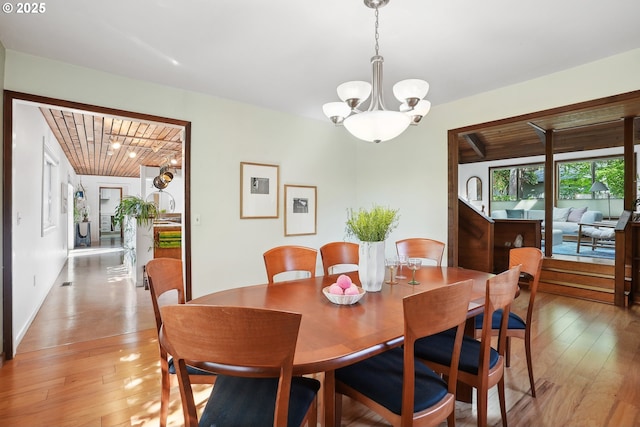 dining space with light wood-style floors, wooden ceiling, and a notable chandelier