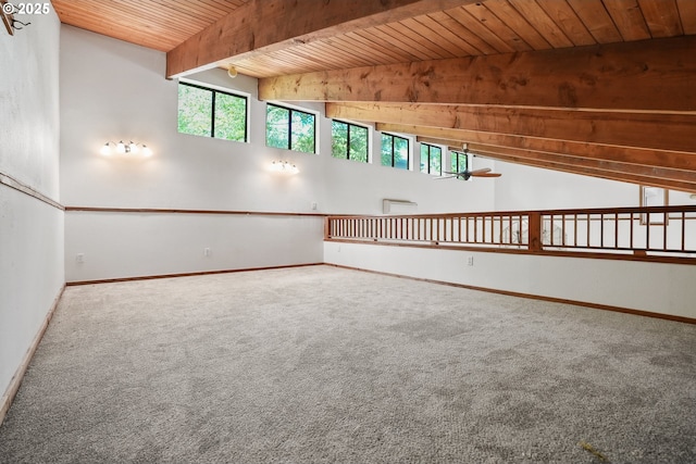 carpeted empty room with baseboards, beam ceiling, a wealth of natural light, and wooden ceiling