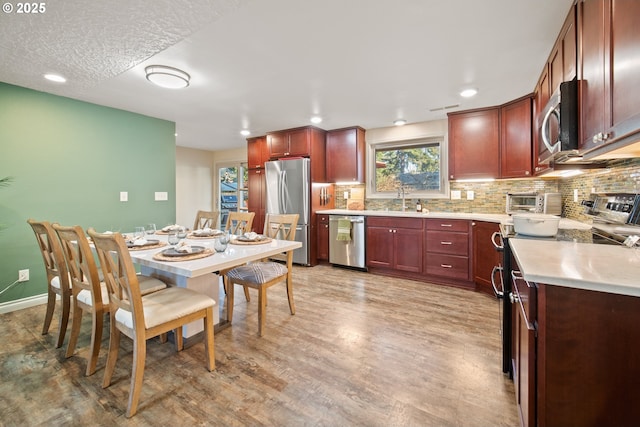 kitchen with sink, light wood-type flooring, decorative backsplash, and stainless steel appliances