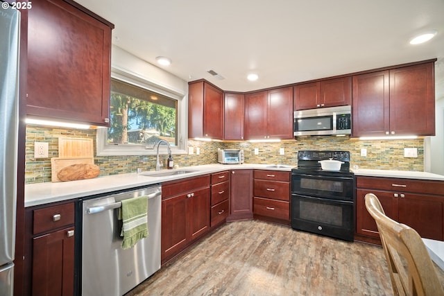 kitchen featuring decorative backsplash, sink, appliances with stainless steel finishes, and light wood-type flooring