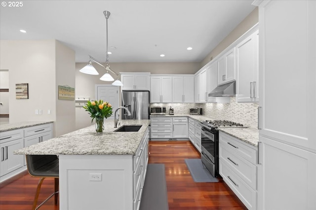 711 NW 94th Ter, Portland, OR 97229 - kitchen with appliances with stainless steel finishes, under cabinet range hood, white cabinetry, decorative backsplash, and dark wood-style floors