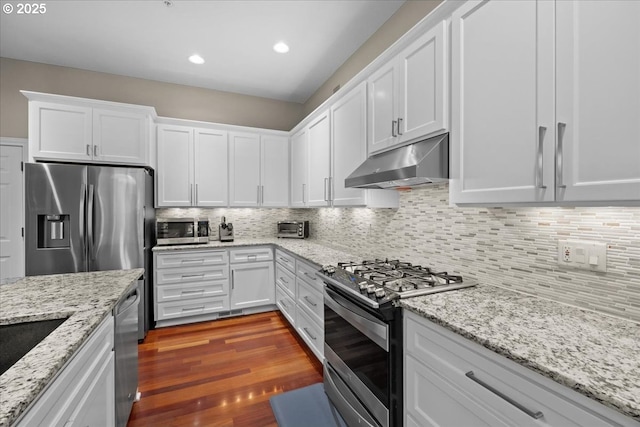 711 NW 94th Ter, Portland, OR 97229 - kitchen featuring appliances with stainless steel finishes, under cabinet range hood, white cabinetry, decorative backsplash, and recessed lighting