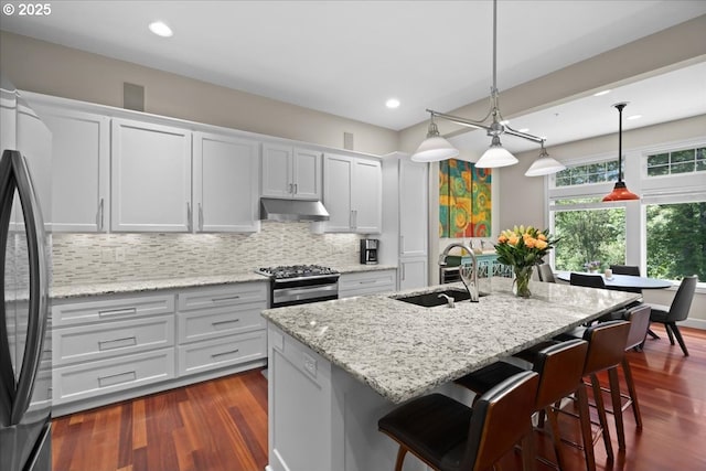 711 NW 94th Ter, Portland, OR 97229 - kitchen with under cabinet range hood, appliances with stainless steel finishes, decorative backsplash, dark wood finished floors, and recessed lighting
