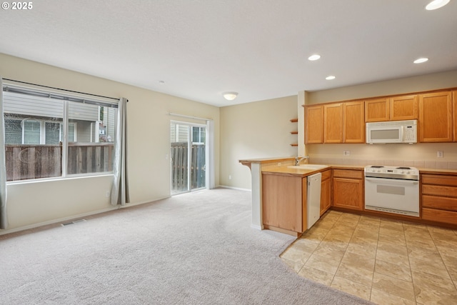 6538 NE Forest Ln, Hillsboro, OR 97124 - kitchen with white appliances, a peninsula, light countertops, light carpet, and recessed lighting