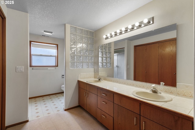 15917 NE Union Rd, Ridgefield, WA 98642 - full bath featuring double vanity, tile patterned floors, toilet, a textured ceiling, and baseboards