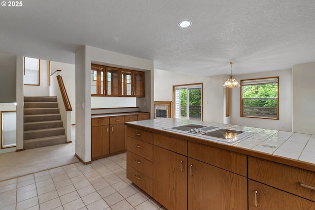 15917 NE Union Rd, Ridgefield, WA 98642 - kitchen featuring tile counters, stovetop with downdraft, a textured ceiling, light colored carpet, and brown cabinets