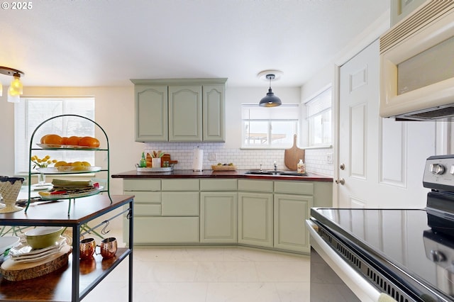 kitchen with stainless steel electric range oven, sink, decorative light fixtures, green cabinets, and tasteful backsplash