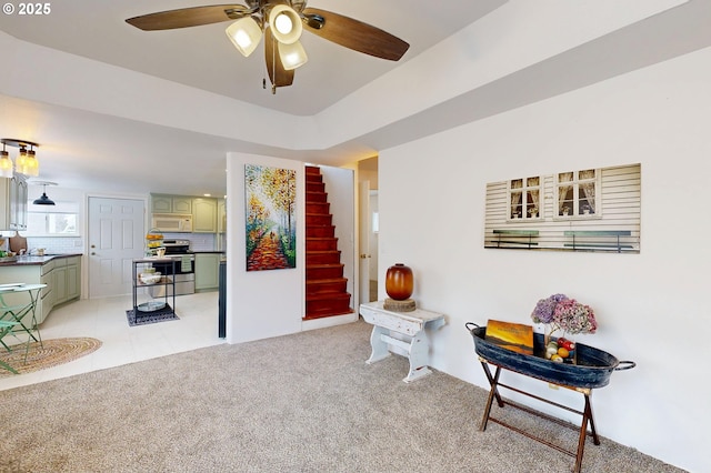 sitting room with ceiling fan, a raised ceiling, and light carpet