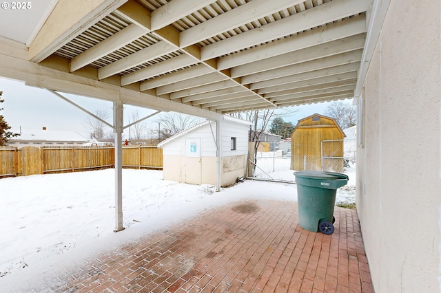 snow covered patio featuring a storage shed