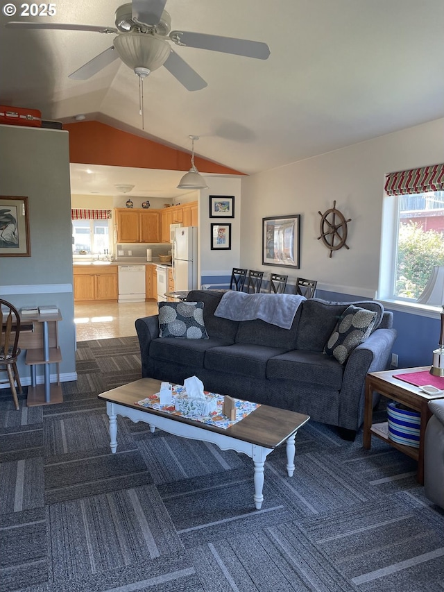 living area featuring carpet, a healthy amount of sunlight, lofted ceiling, and ceiling fan
