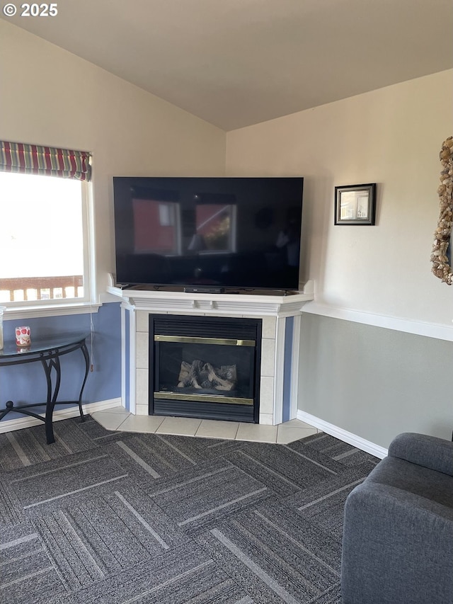 carpeted living room featuring baseboards, vaulted ceiling, and a tiled fireplace