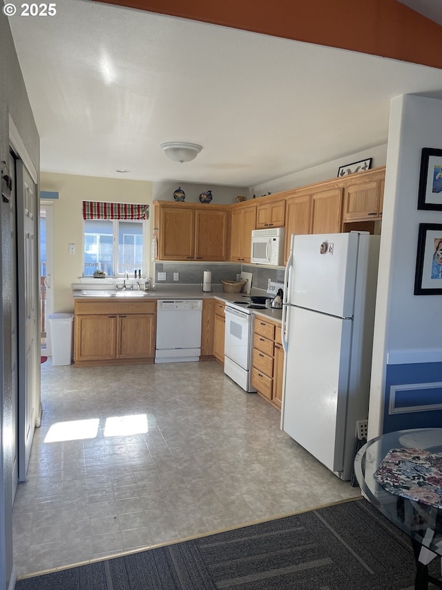 kitchen with light countertops, a sink, light floors, and white appliances