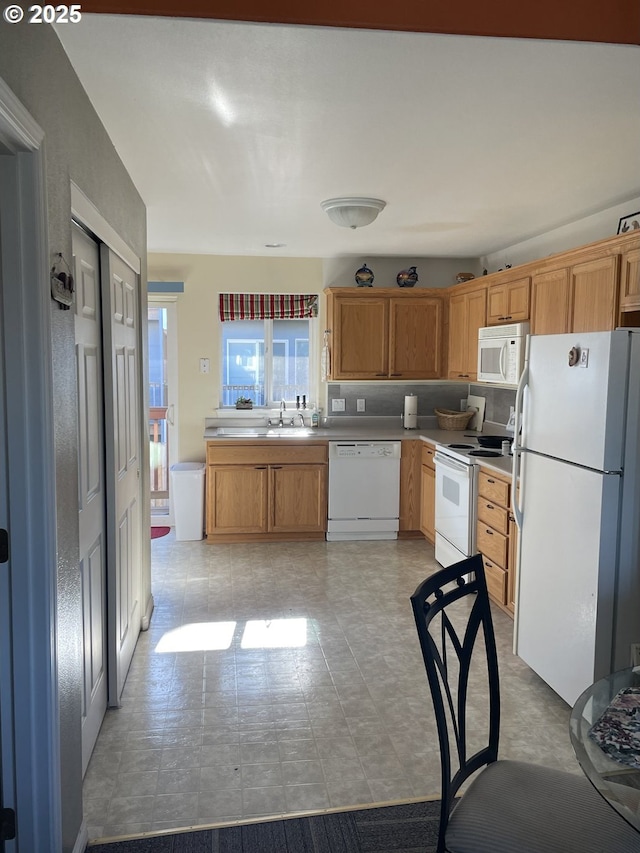 kitchen featuring white appliances, light countertops, and a sink
