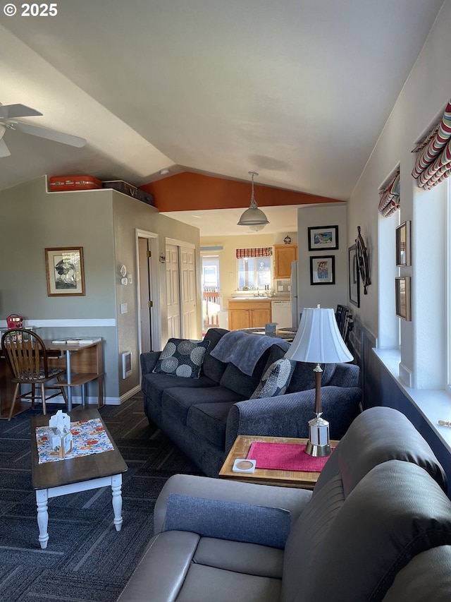 living room featuring baseboards, ceiling fan, vaulted ceiling, and dark colored carpet