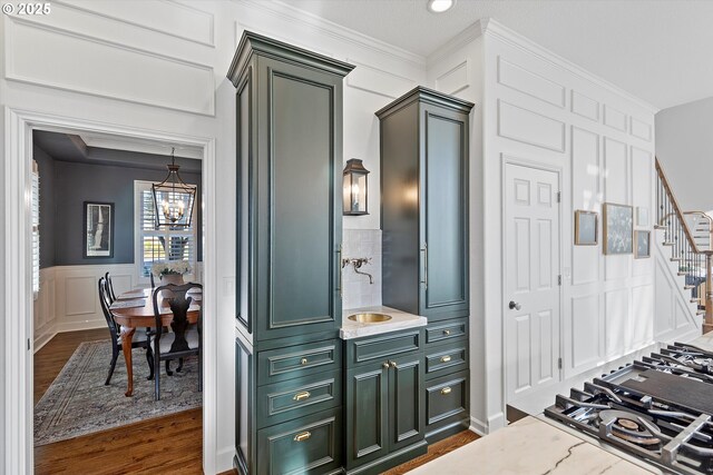 kitchen with sink, an inviting chandelier, ornamental molding, dark hardwood / wood-style flooring, and light stone countertops