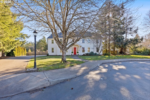 view of front facade with fence, driveway, and a front lawn