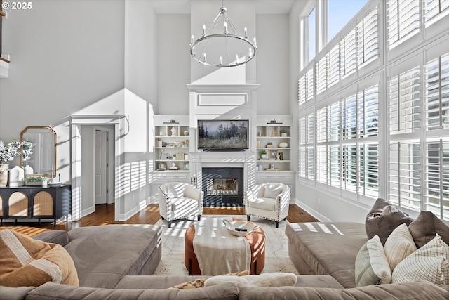 living room with wood finished floors, a healthy amount of sunlight, a glass covered fireplace, and an inviting chandelier