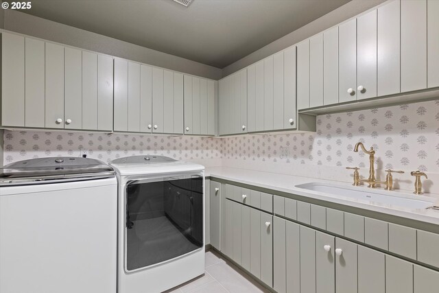 washroom featuring sink, light tile patterned floors, cabinets, and washer and dryer