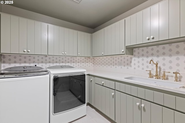 laundry room with light tile patterned flooring, cabinets, sink, and washing machine and dryer