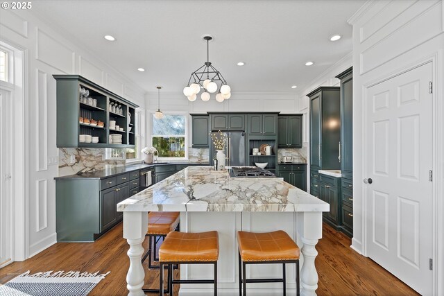 kitchen featuring pendant lighting, crown molding, stainless steel refrigerator, a center island, and dark hardwood / wood-style flooring