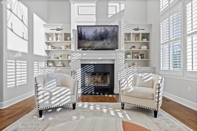 sitting room featuring baseboards, wood finished floors, and a glass covered fireplace