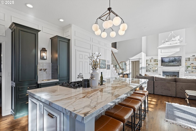 kitchen featuring pendant lighting, dark wood-type flooring, light stone countertops, a kitchen island, and a chandelier