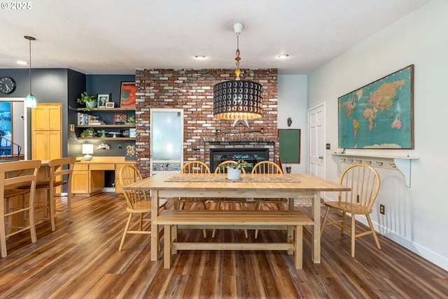 8836 SW 56th Ave, Portland, OR 97219 - dining room featuring wood finished floors, a brick fireplace, a textured ceiling, and baseboards
