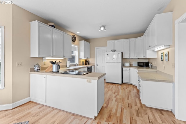 33310 Cape Kiwanda Dr, Pacific City, OR 97135 - kitchen with black appliances, a peninsula, light wood-style flooring, light countertops, and a sink