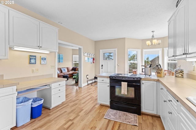 33310 Cape Kiwanda Dr, Pacific City, OR 97135 - kitchen featuring black range with electric cooktop, white cabinets, a chandelier, light wood finished floors, and a peninsula