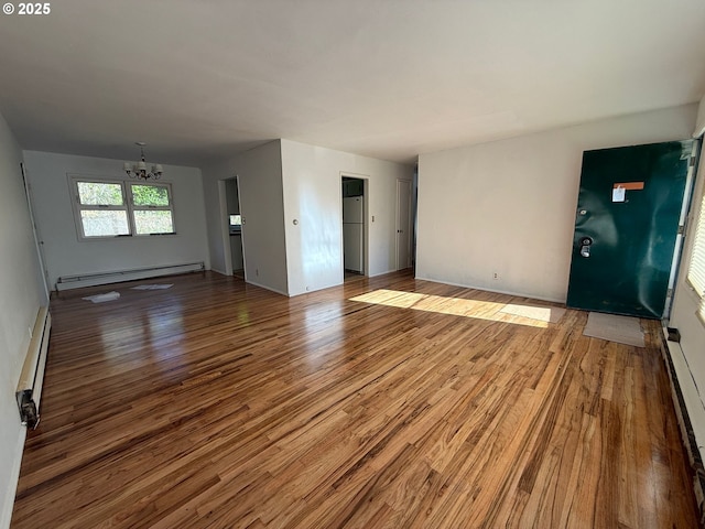 unfurnished living room featuring hardwood / wood-style flooring, an inviting chandelier, and a baseboard radiator