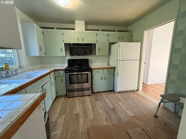 kitchen with tile countertops, light hardwood / wood-style floors, stainless steel electric range, white refrigerator, and sink