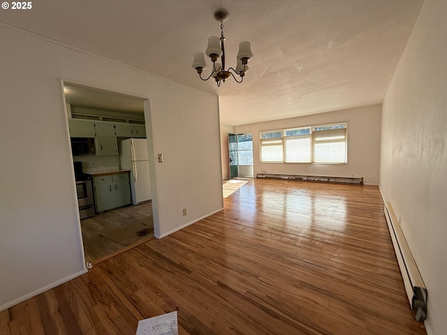 unfurnished living room with baseboard heating, hardwood / wood-style floors, and a chandelier