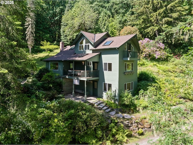 14207 NW Newberry Rd, Portland, OR 97231 - view of front of property with a balcony, a chimney, a forest view, and a patio