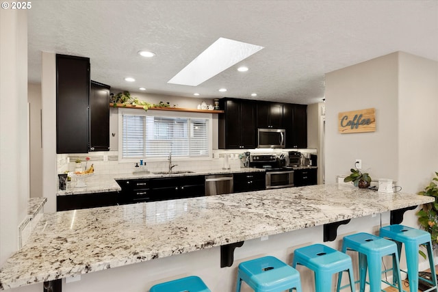 kitchen featuring a breakfast bar, appliances with stainless steel finishes, a skylight, and sink