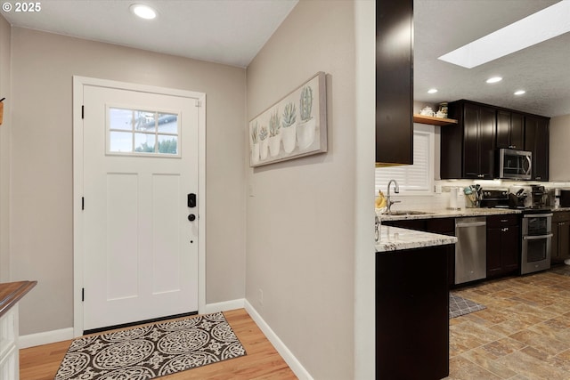 foyer featuring sink, a skylight, and light wood-type flooring