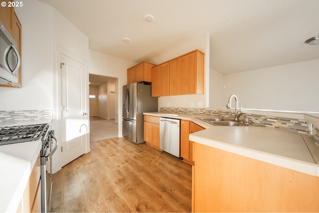 kitchen with sink, tasteful backsplash, light wood-type flooring, kitchen peninsula, and stainless steel appliances