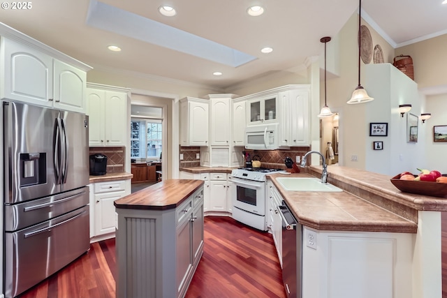 kitchen featuring appliances with stainless steel finishes, decorative light fixtures, sink, white cabinets, and kitchen peninsula