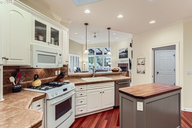 kitchen with pendant lighting, white cabinetry, sink, a center island, and white appliances