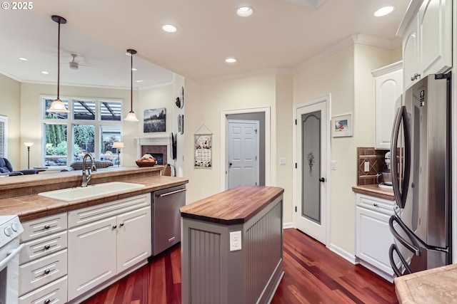 kitchen with wood counters, sink, white cabinets, a center island, and stainless steel appliances