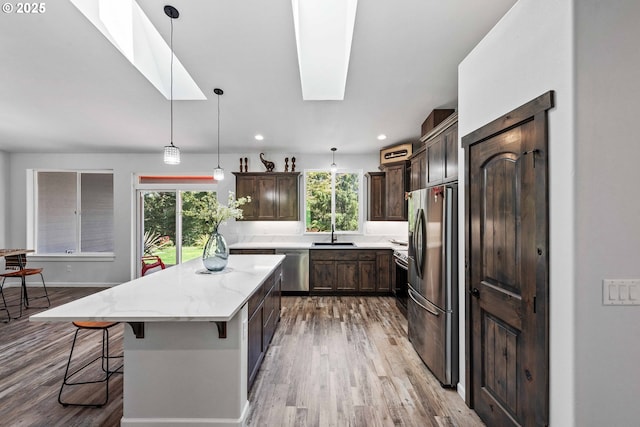 69857 Stage Rd, North Bend, OR 97459 - kitchen featuring appliances with stainless steel finishes, a skylight, a sink, a kitchen island, and dark brown cabinetry