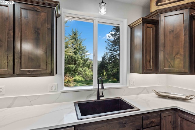 69857 Stage Rd, North Bend, OR 97459 - kitchen with a sink, dark brown cabinets, light stone counters, and hanging light fixtures