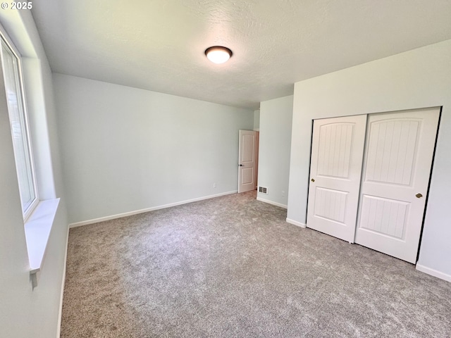 69857 Stage Rd, North Bend, OR 97459 - unfurnished bedroom with carpet floors, a closet, baseboards, and a textured ceiling