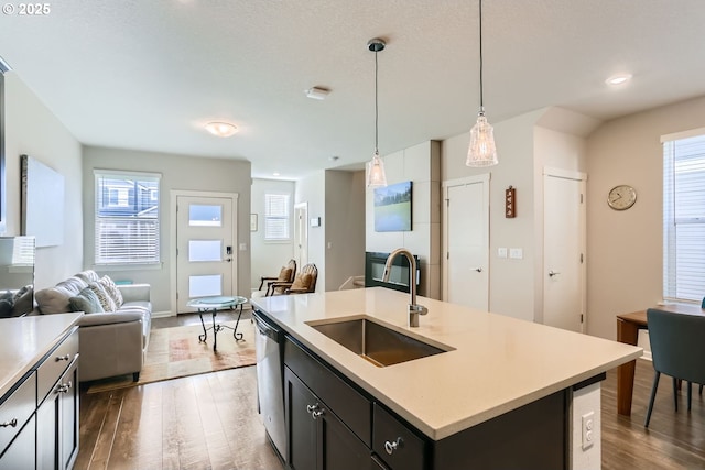 kitchen featuring sink, dark hardwood / wood-style flooring, dishwasher, an island with sink, and pendant lighting