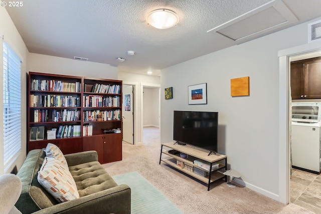 carpeted living room with washer / clothes dryer and a textured ceiling