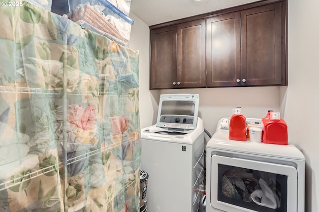 clothes washing area with washer and clothes dryer and cabinets