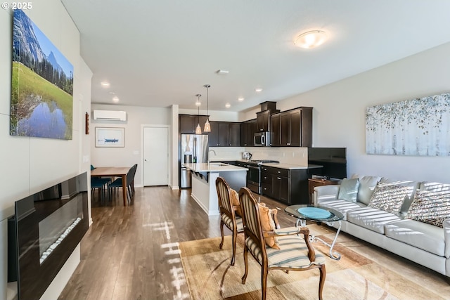 living room featuring sink, light hardwood / wood-style floors, and a wall unit AC