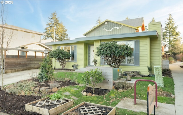 view of front of property featuring board and batten siding, a vegetable garden, and fence