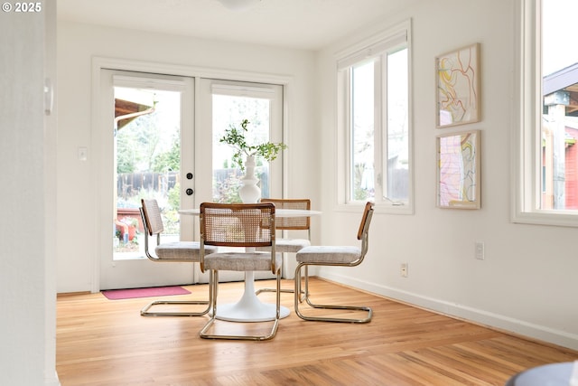 dining room featuring french doors, a healthy amount of sunlight, baseboards, and wood finished floors