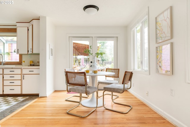 sitting room featuring light wood-type flooring, plenty of natural light, baseboards, and french doors