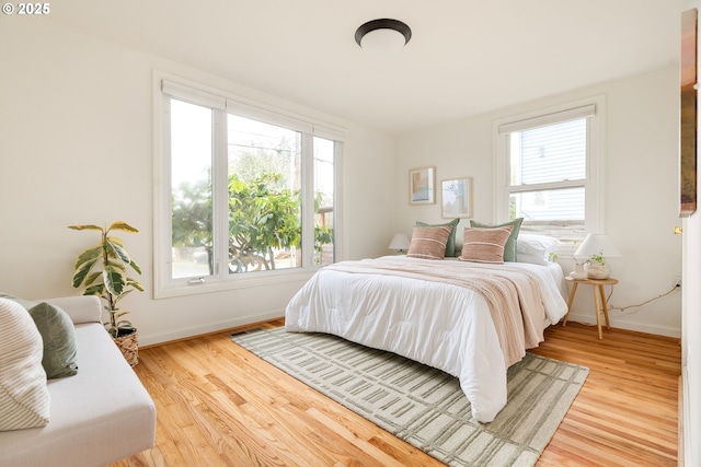 bedroom featuring light wood finished floors, multiple windows, and visible vents